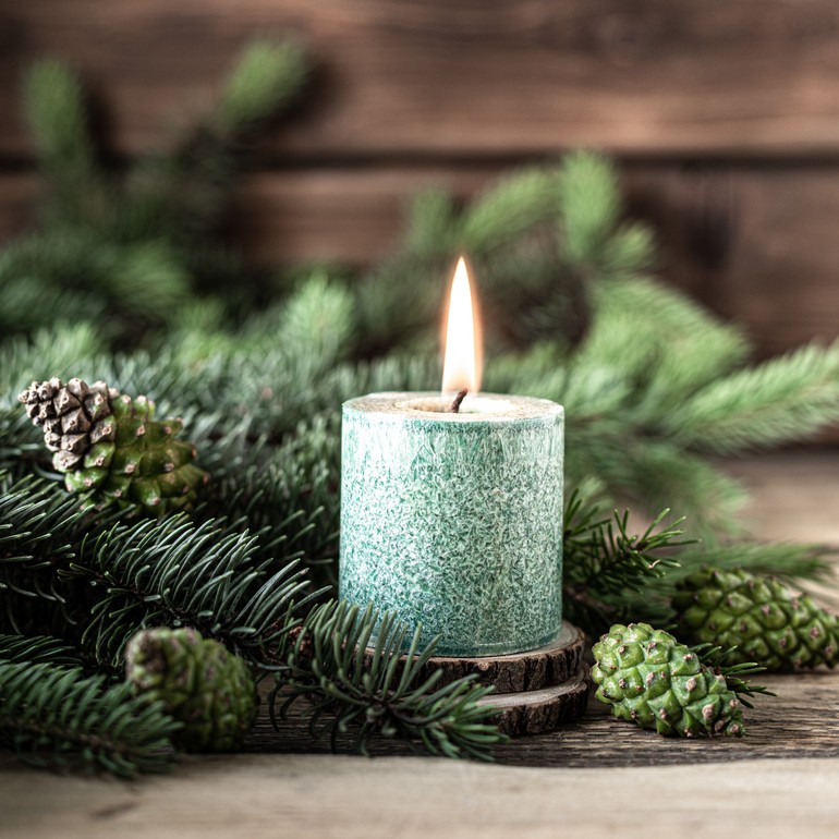 Christmas green candle with fir branches and cones on wooden table, copy space